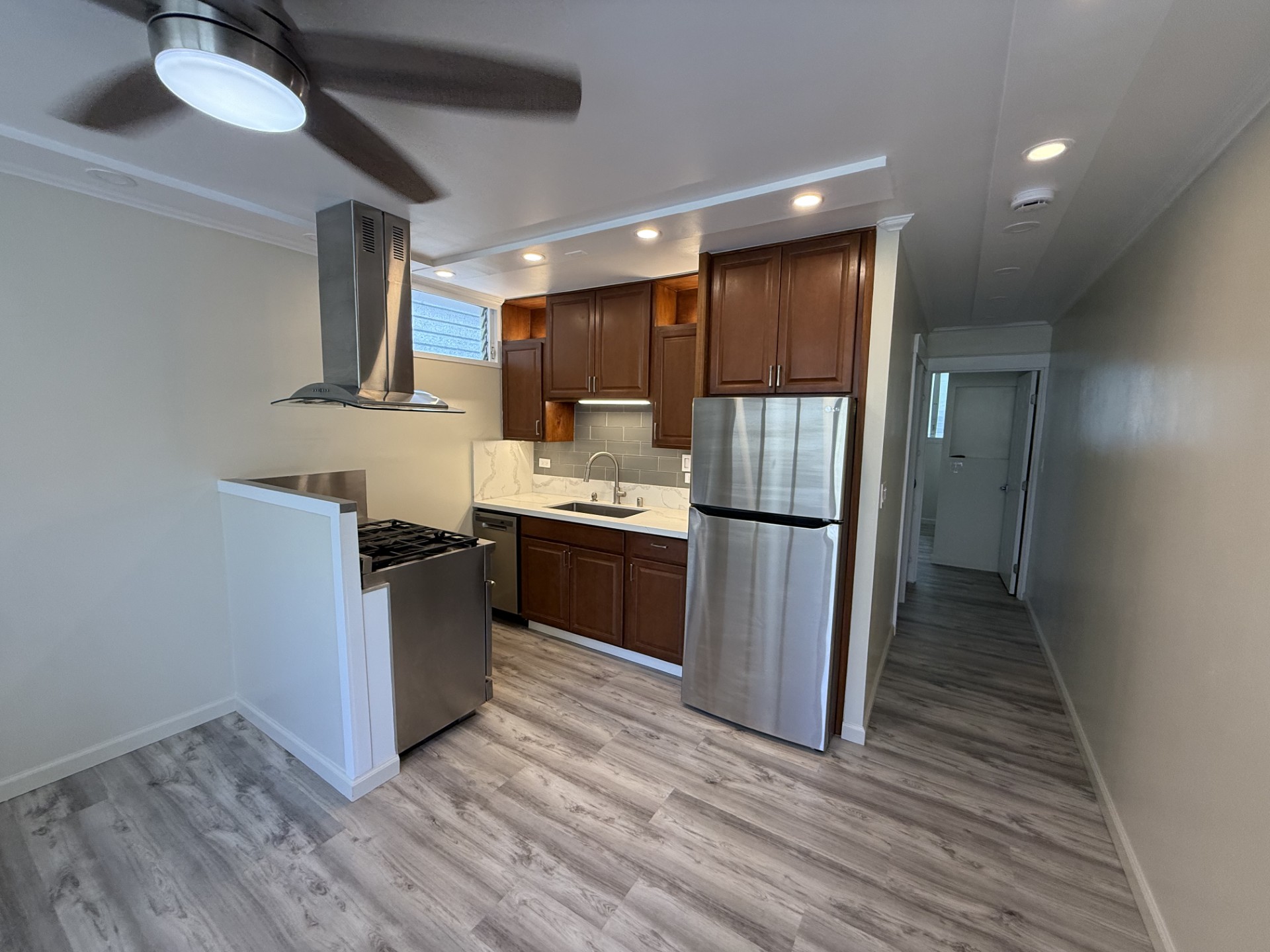 A modern kitchen with a wood grain floor and white walls.